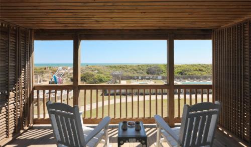 a screened in porch with two chairs and a table at The Sanderling in Duck