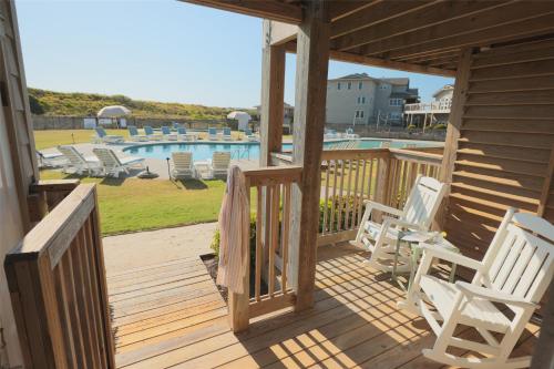 a wooden deck with chairs and a swimming pool at The Sanderling in Duck