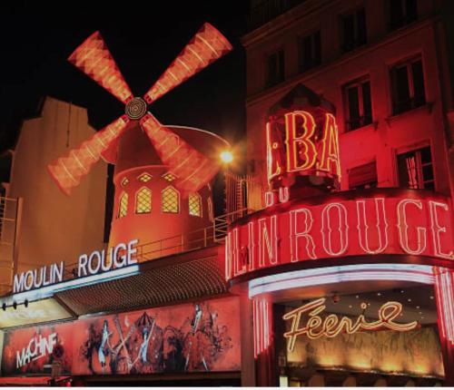 un bâtiment avec une enseigne et un moulin à vent dessus dans l'établissement Sympathy Studio For 2 Near The Sacre Coeur, à Paris