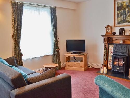 sala de estar con sofá, TV y chimenea en Bert's Cottage, en Fordingbridge