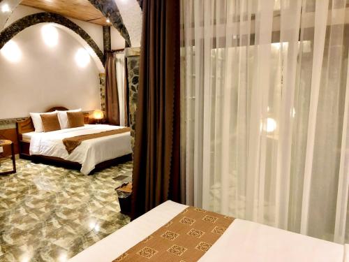 a bedroom with two beds and a large window at Sầm Sơn Boutique Hotel Phan Thiết in Phan Thiet