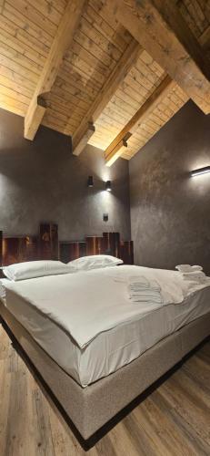 a large white bed in a room with wooden ceilings at Crimea Wine Hotel in Chiavenna