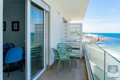 a balcony with a table and chairs and the ocean at Villa Mediterranea Apartments - Seaview, Pool & Garden in Bari