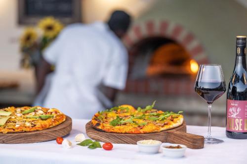 two pizzas sitting on a table with a glass of wine at Safari Lodge in Windhoek