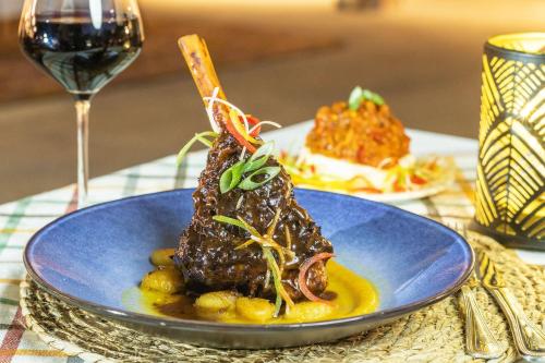 a plate of food on a table with a glass of wine at Safari Lodge in Windhoek