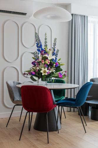 a dining room with a table and chairs with a vase of flowers at Wings Plaza in Kraków