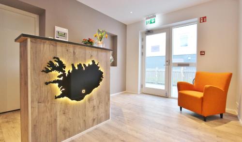 a room with an orange chair and a wooden wall at Lava Apartments & Rooms in Akureyri