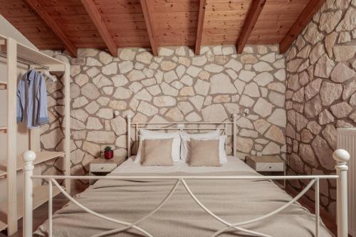 a bedroom with a bed in a stone wall at Arca Villa - Enchanting Sunset! in Keri