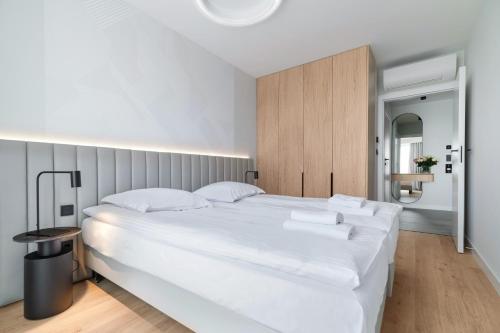 a white bedroom with a large white bed with white pillows at Wings Plaza in Kraków