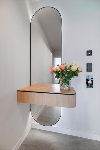 a dressing table with a mirror and a vase of flowers at Wings Plaza in Kraków