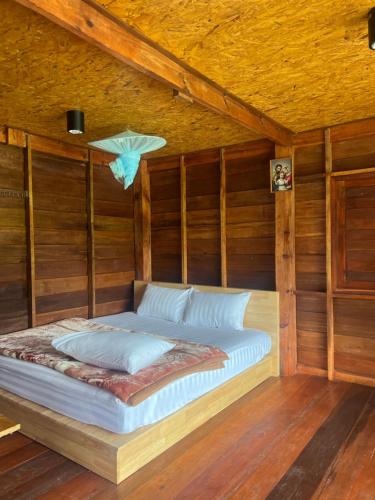 a bed in a room with wooden walls at บ้านพักป้าซู อินทนนท์ in Ban Yang