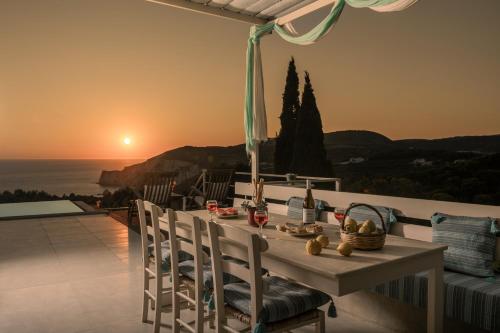 a table and chairs on a balcony with the sunset at Arca Villa - Enchanting Sunset! in Keri