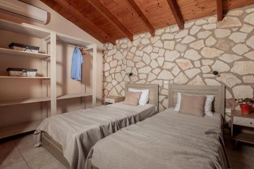 two beds in a room with a stone wall at Arca Villa - Enchanting Sunset! in Keri