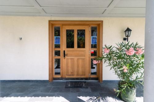 a wooden door of a house with flowers at Room's at HAUS am SEE direkt am Thunersee gelegen mit SELF CHECK IN & digitaler Rezeption in Oberhofen am Thunersee