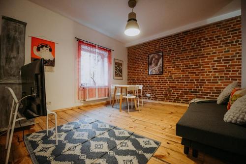 a living room with a couch and a brick wall at Off Piotrkowska Spot in Łódź