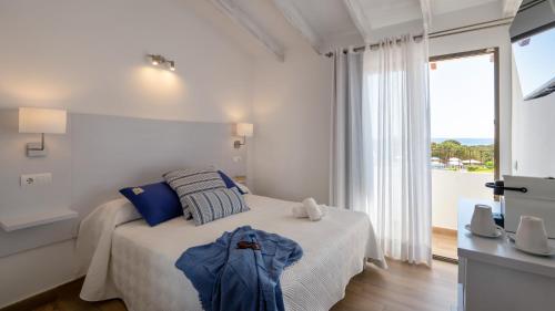 a white bedroom with a bed and a large window at Hotel Rosamar - Emar Hotels in Es Pujols