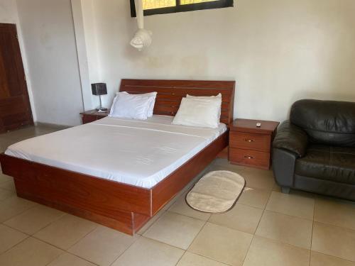 a bed in a room with a couch and a bed sidx sidx sidx at Pension Les Palmiers in Kipé