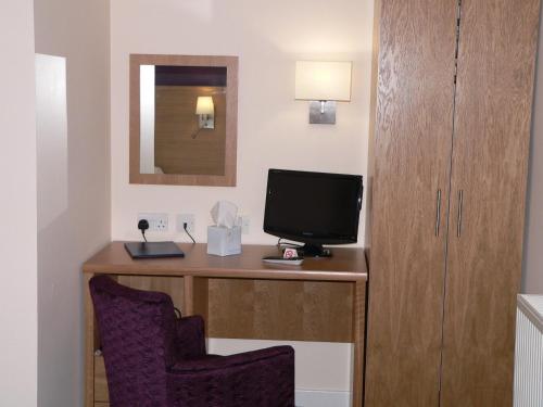 a room with a desk with a tv and a chair at Ayre Hotel & Ayre Apartments in Kirkwall