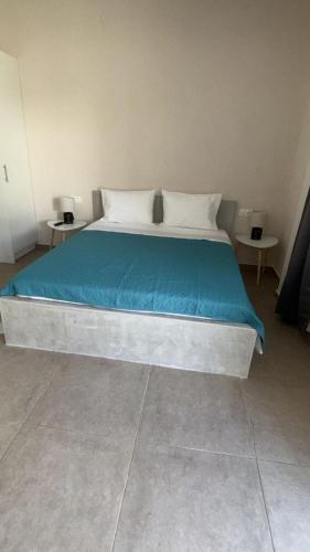 a bedroom with a bed with blue sheets and two tables at Sunset Realty Studios in Kinion