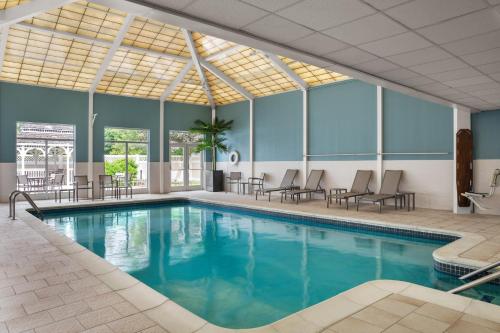 a pool with chairs and tables in a building at Holiday Inn Express & Suites Hawthorne - Elmsford North by IHG in Hawthorne
