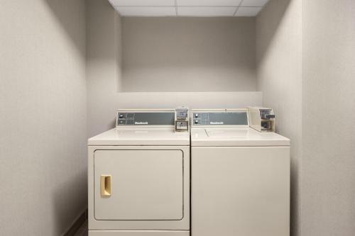 a laundry room with two washers and a refrigerator at Holiday Inn Express & Suites Hawthorne - Elmsford North by IHG in Hawthorne