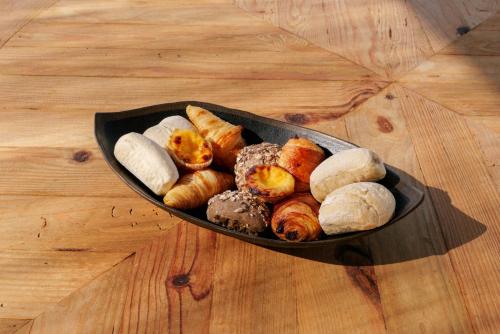 Un plato de pan y pasteles sobre un suelo de madera. en Masana Algarve, en Albufeira