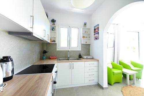 a kitchen with white cabinets and a green chair at Anchor Villa in Troulos