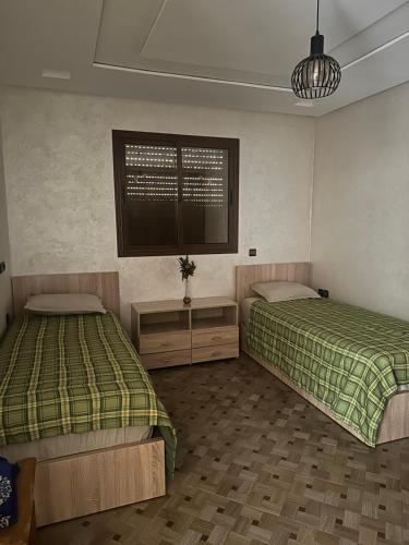 a room with two beds and a window in it at Petite villa palmeraie d Aglou in Tiznit