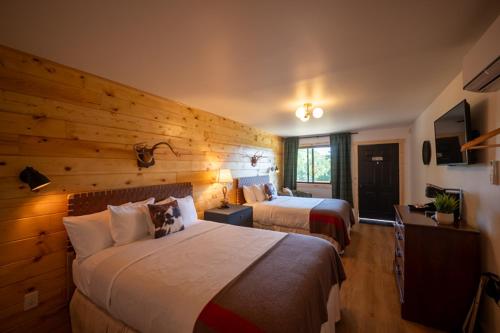 a hotel room with two beds and a wooden wall at The Woodsman Lodge in Eureka Springs