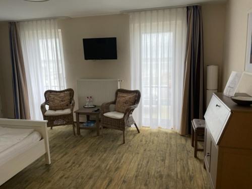a hotel room with a bed and chairs and a television at Hotel Admiral Scheer in Laboe