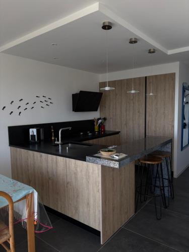 - une cuisine avec un plan de travail noir et un évier dans l'établissement Rêve bleu, au Grau-du-Roi