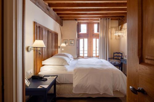 a bedroom with a bed and a desk and a window at Le Champ des Oiseaux Hôtel & Spa in Troyes