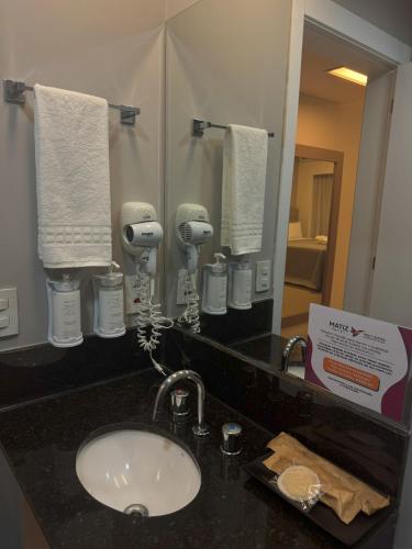 a bathroom counter with a sink and a mirror at Matiz Multi Suites in Duque de Caxias