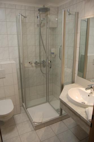 a bathroom with a shower and a toilet and a sink at Hotel Admiral Scheer in Laboe