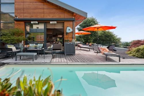 a house with a pool and a patio with an umbrella at Exquisite 5-Bedroom Villa in Arzier for Families by GuestLee in Arzier