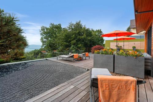 a deck with a table and chairs and an umbrella at Exquisite 5-Bedroom Villa in Arzier for Families by GuestLee in Arzier