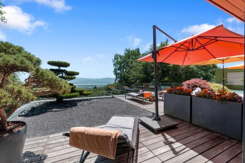 a patio with an umbrella and a table and chairs at Exquisite 5-Bedroom Villa in Arzier for Families by GuestLee in Arzier