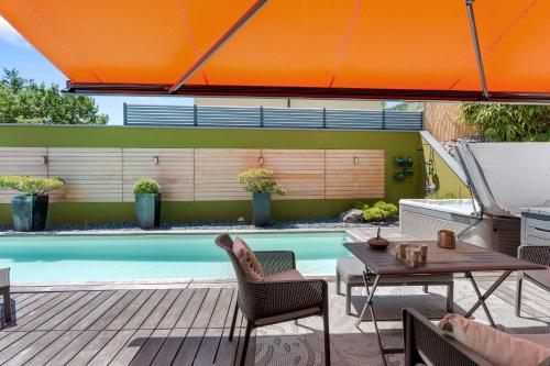 an orange umbrella over a table and chairs next to a swimming pool at Exquisite 5-Bedroom Villa in Arzier for Families by GuestLee in Arzier