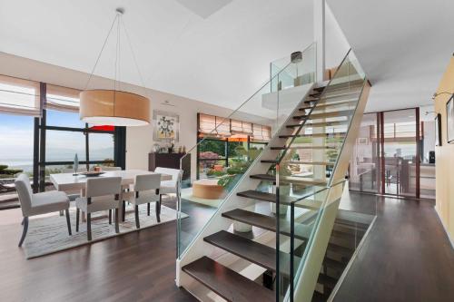 a glass staircase in a dining room with a dining table at Exquisite 5-Bedroom Villa in Arzier for Families by GuestLee in Arzier