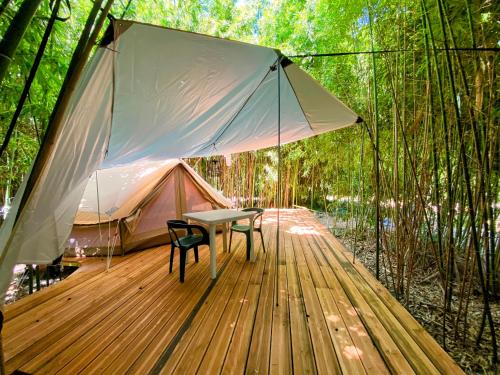 une terrasse en bois avec une table et une tente dans l'établissement Camping les Avenières, à Manthes