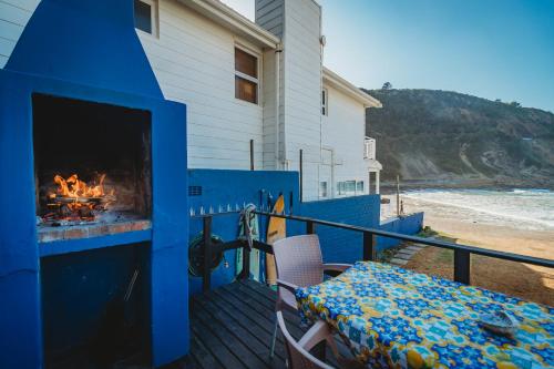 a blue fireplace on a deck with a table and chairs at Silver Spray Beach Accommodation in Victoria Bay