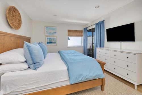 a bedroom with a bed with blue pillows and a tv at Shipwatch #311 in Saint Simons Island