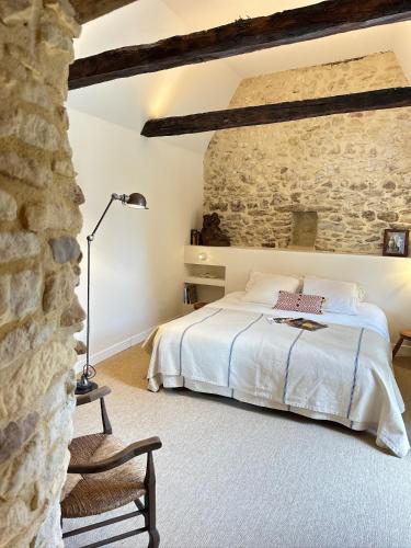 une chambre avec un lit et un mur en pierre dans l'établissement Maison Cazenac, à Beynac-et-Cazenac