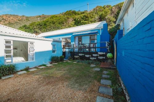 a blue and white house with a hill in the background at Silver Spray Beach Accommodation in Victoria Bay