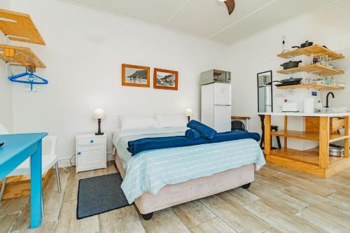 a bedroom with a bed and a desk and a kitchen at Silver Spray Beach Accommodation in Victoria Bay