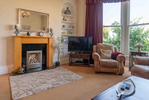 Una sala de estar con chimenea y televisión. en 2 Bath House, en Ilfracombe