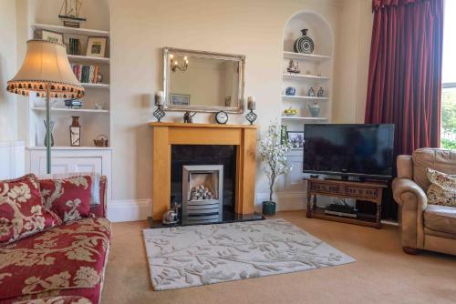 Una sala de estar con chimenea y televisión. en 2 Bath House, en Ilfracombe