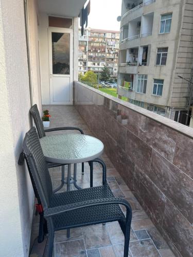 a table and chairs on a balcony with a window at ბინა დღიურად in Kakhaberi