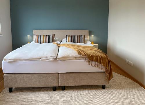 a bedroom with a bed with white sheets and pillows at "FIVE" Premium Apartments Seekirchen - exklusive 4-Zi-Penthouse-Wohnung in Seekirchen am Wallersee