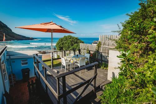 a patio with a table and an umbrella and the ocean at Silver Spray Beach Accommodation in Victoria Bay